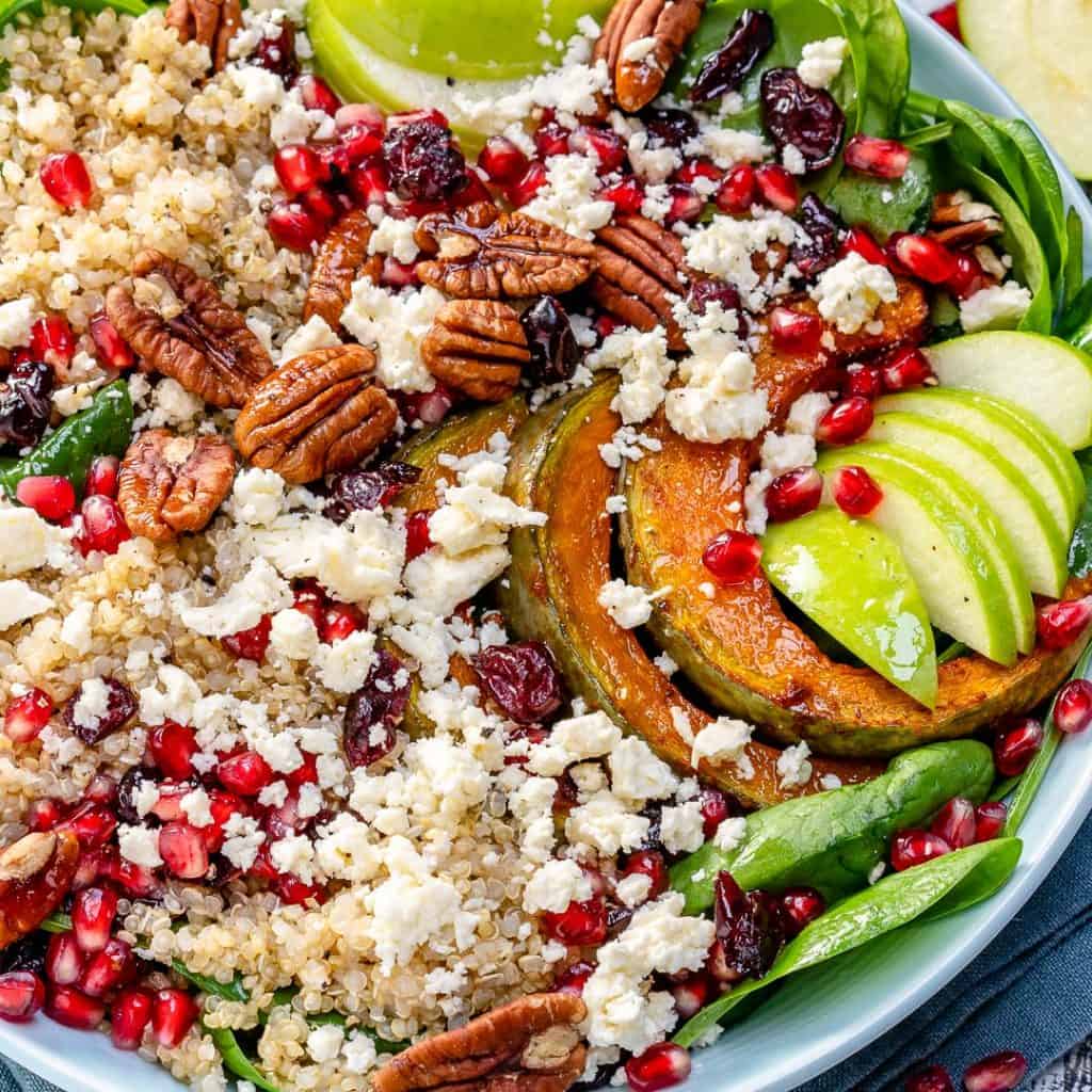 close up image of a salad bowl with quinoa, spinach, apples, feta, and pomegranate