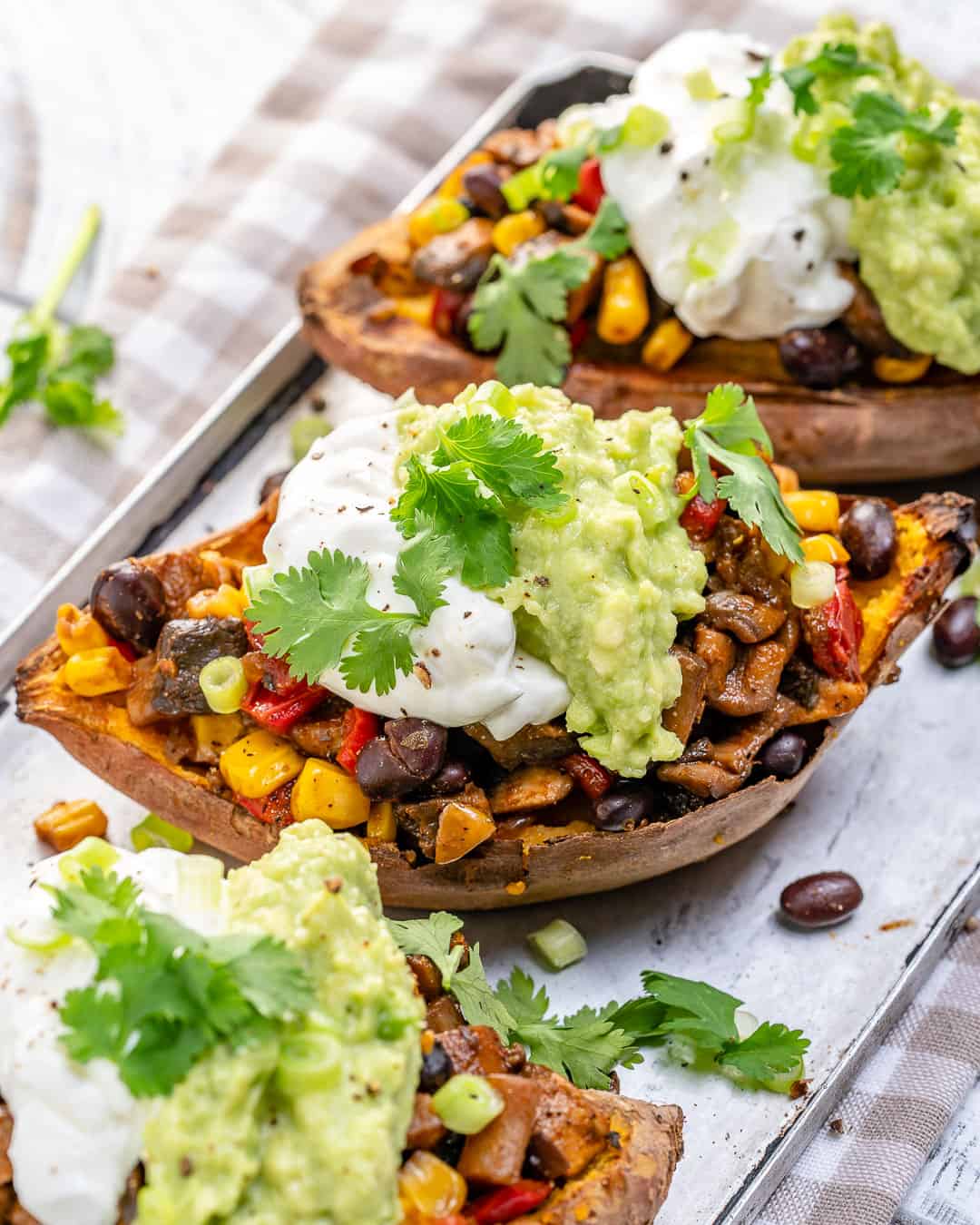 baked sweet potato recipe stuffed with taco mixture and topped with avocado, yogurt, and cilantro 