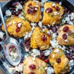 roasted chicken thighs in a black skillet with cranberries and feta cheese