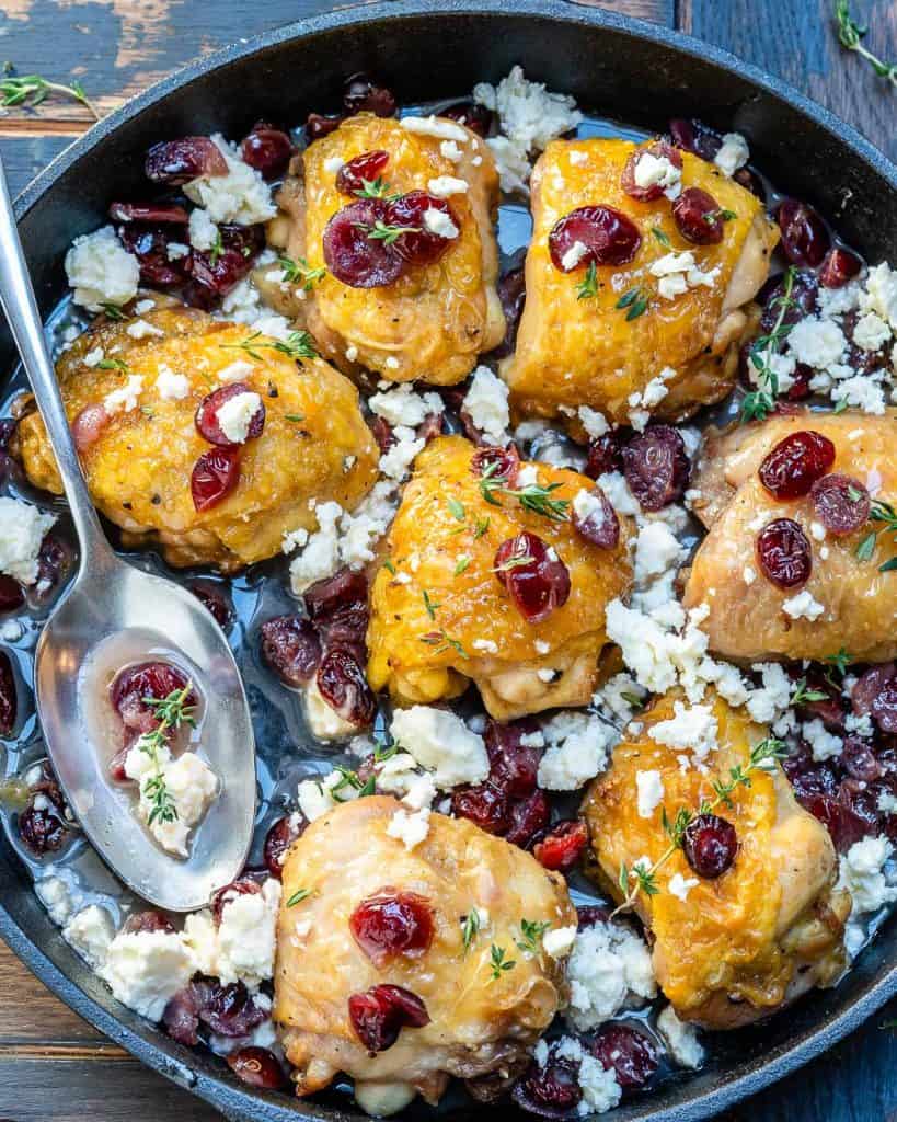 roasted chicken thighs in a black skillet with cranberries and feta cheese