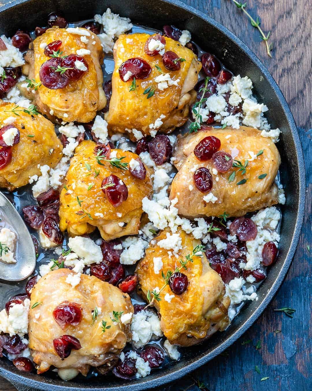 overhead shot of chicken thighs topped with feta cheese and cranberries