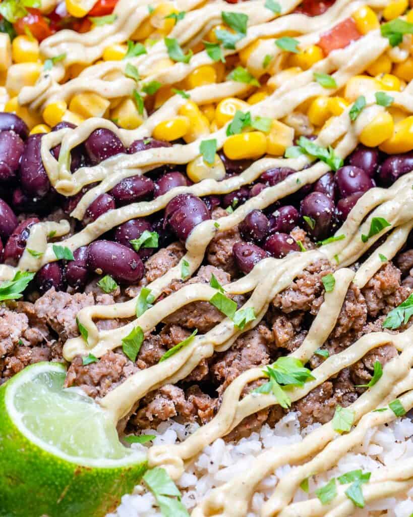 close up view of burrito bowl with ground beef, rice, beans, and corn