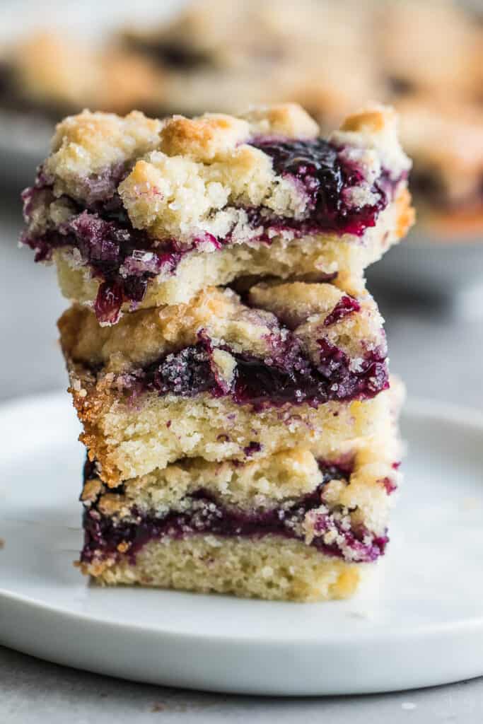side shot stacked up blueberry crumble bars on a round white plate 
