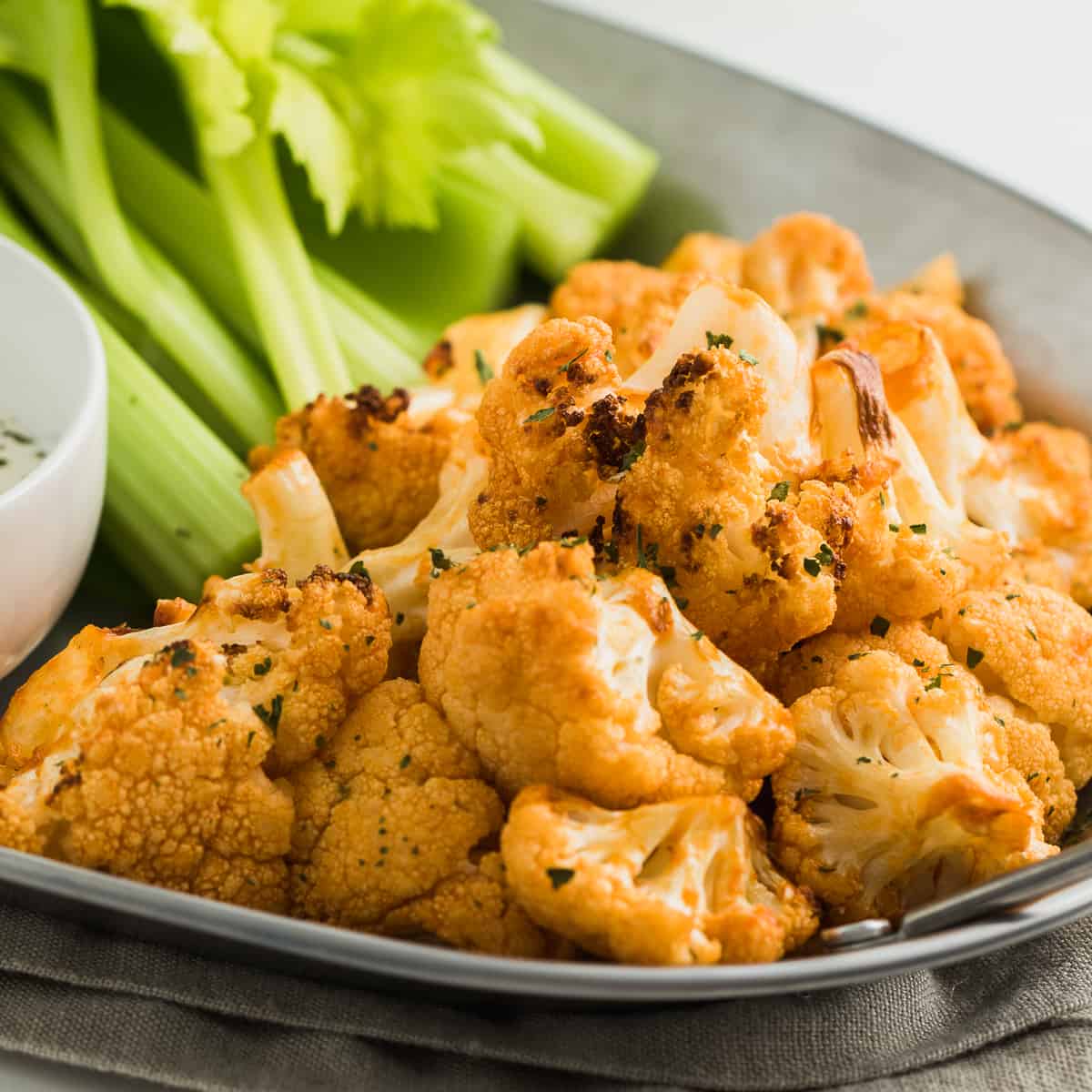 Buffalo Cauliflower bites on plate with celery and dipping sauce