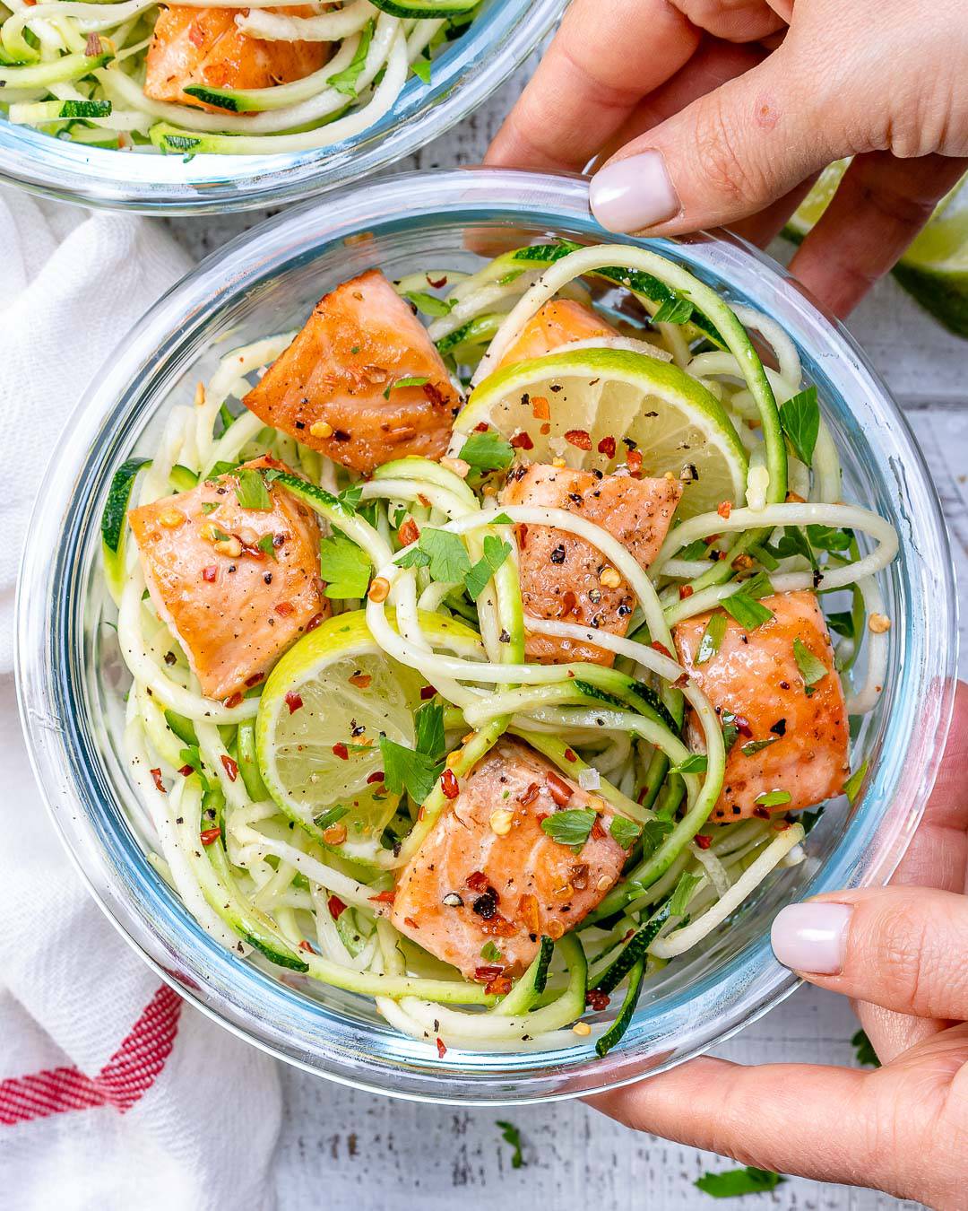 hand holding a container with chili salmon inside. 