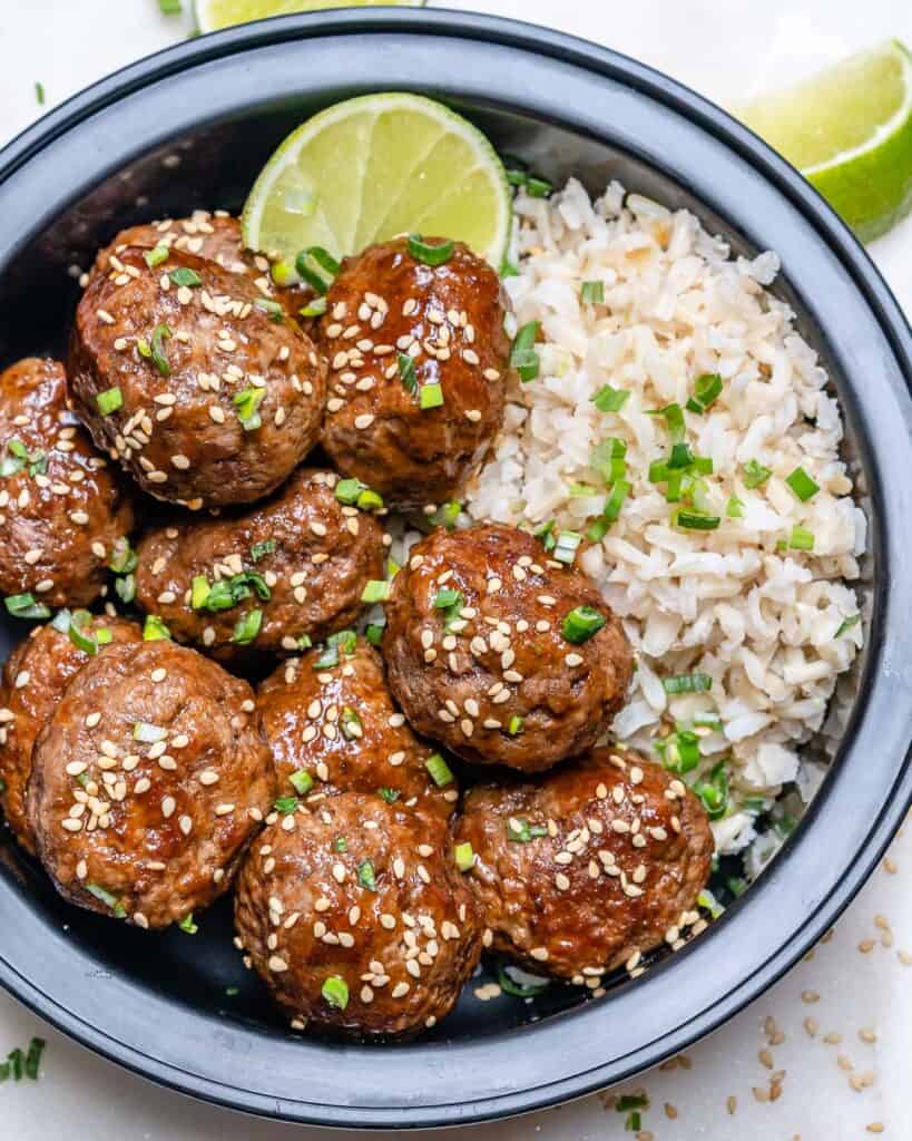 top view of honey meatballs in a black bowl with rice 