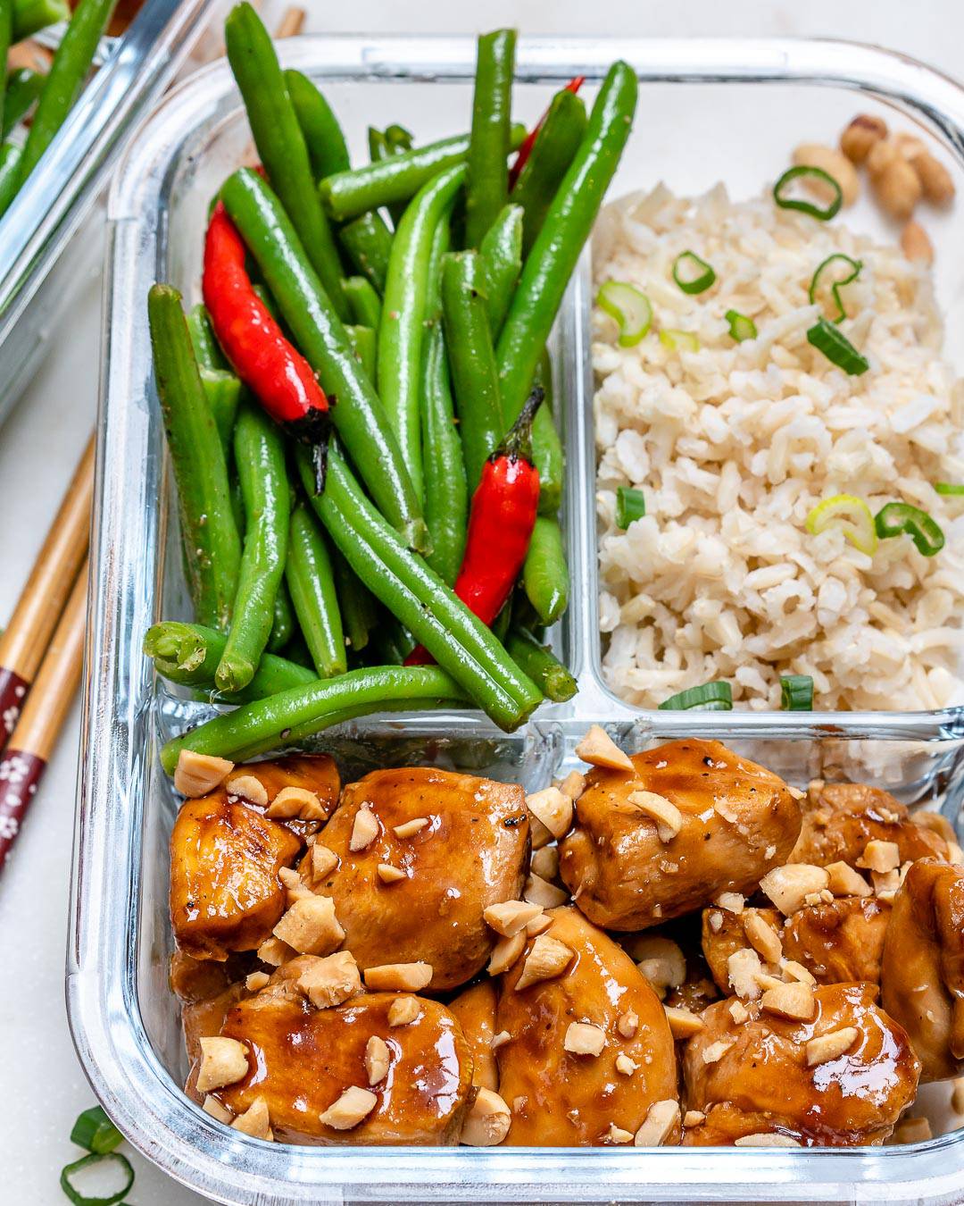 Kung pao chicken in a glass container with beans and rice.