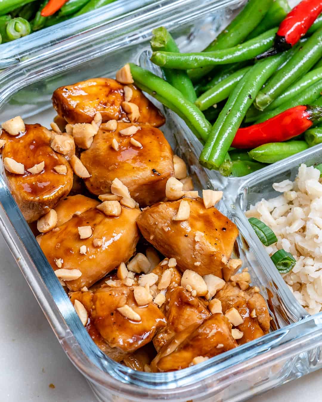 overhead shot of chicken in a container with beans and rice.