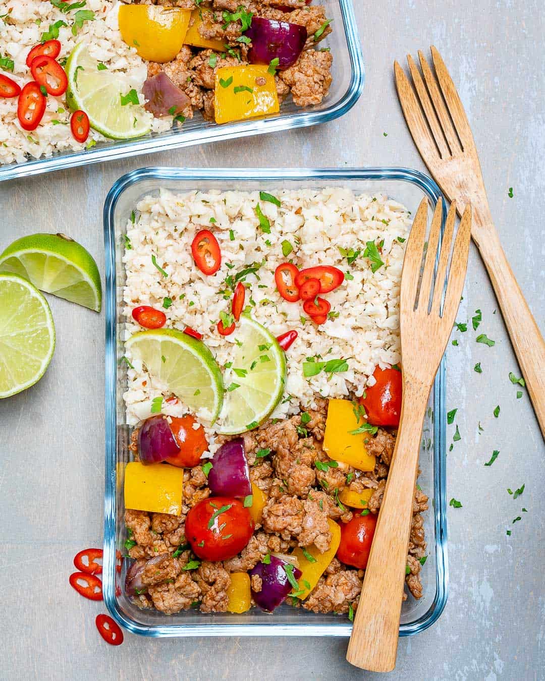 cauliflower rice and ground turkey in glass containers with veggies and forks 