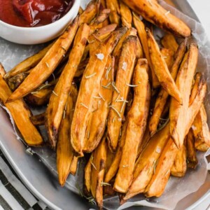 Top view baked sweet potato fries on a plate with a side of ketchup in a bowl