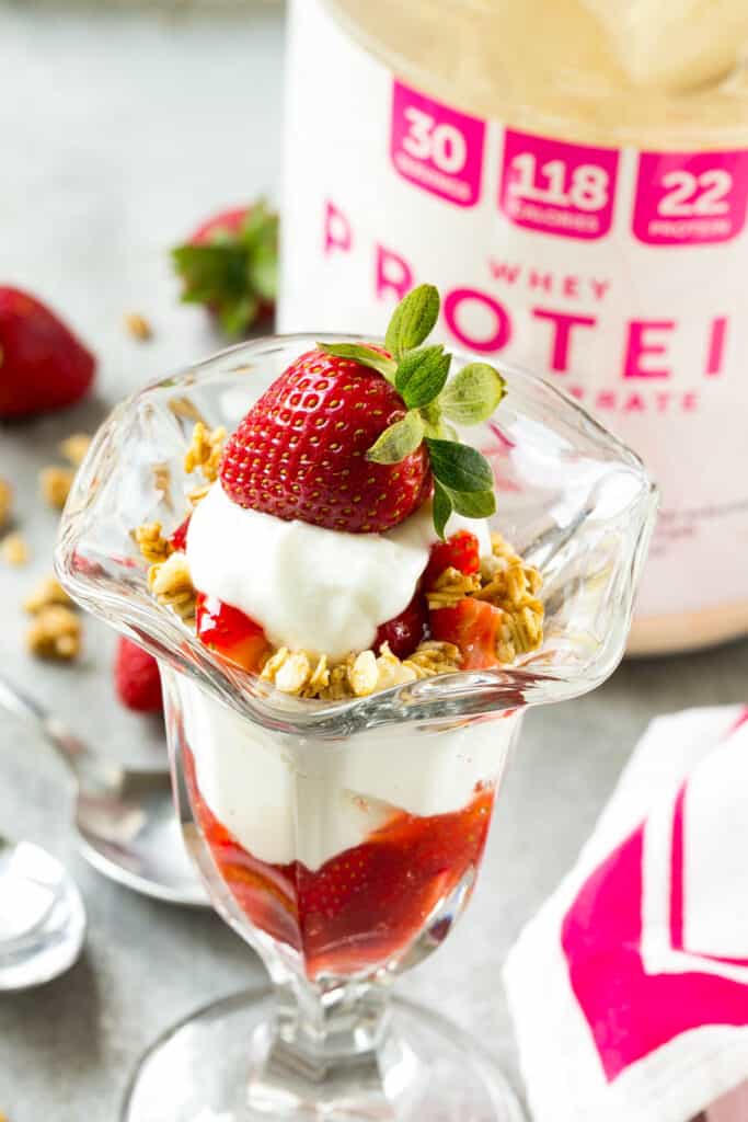 side shot of strawberry parfait in a jar next to a protein tub