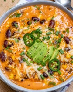 top view of chicken enchilada soup in a round bowl topped with sliced avocado