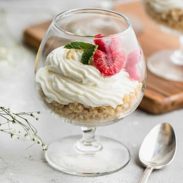 cheesecake in a cup with raspberry and mint garnish.