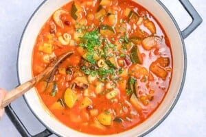 chopped parsley added over the vegetable soup in a pot.