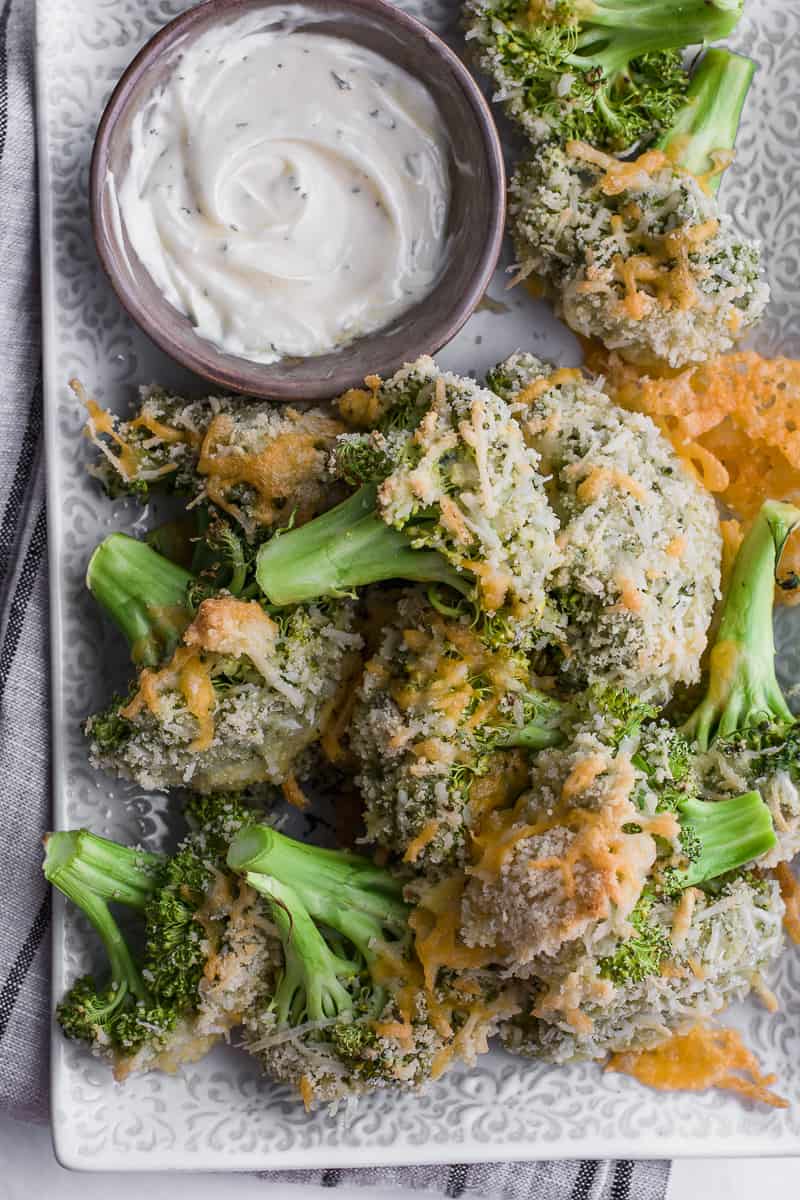 baked broccoli on a plate with a side of dipping sauce.