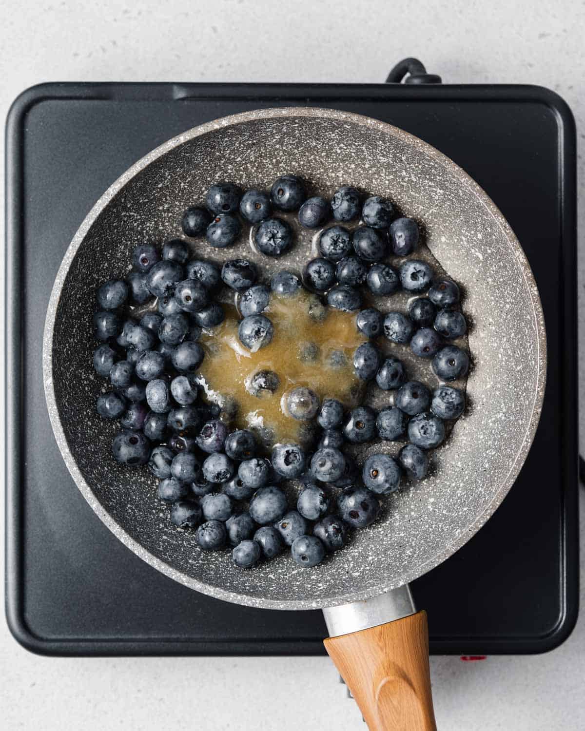 fresh blueberries, honey, and lemon juice placed in a pan.