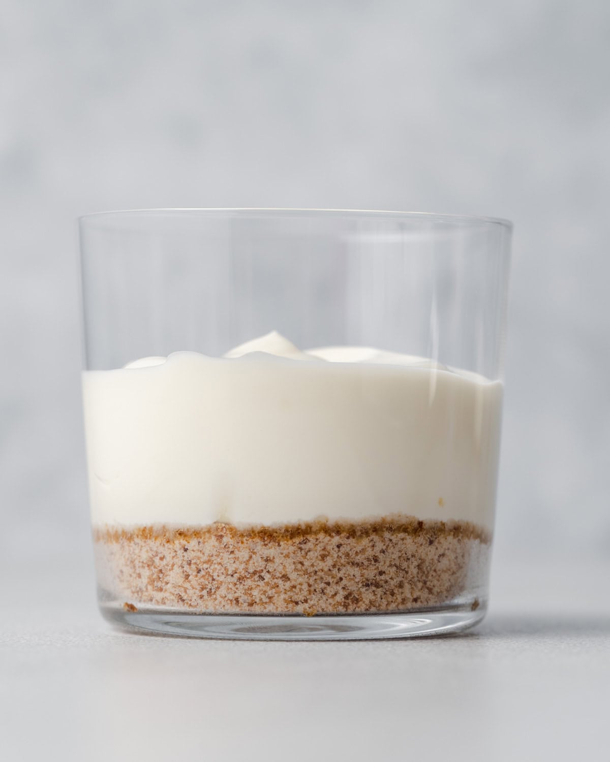 a cup with a layer of crust and a layer of no-bake cheesecake over the crust.