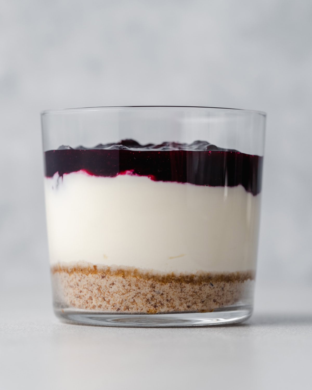 a cup showing the layered cheesecake, Bottom crust layer, then cheesecake filling, then blueberry topping.