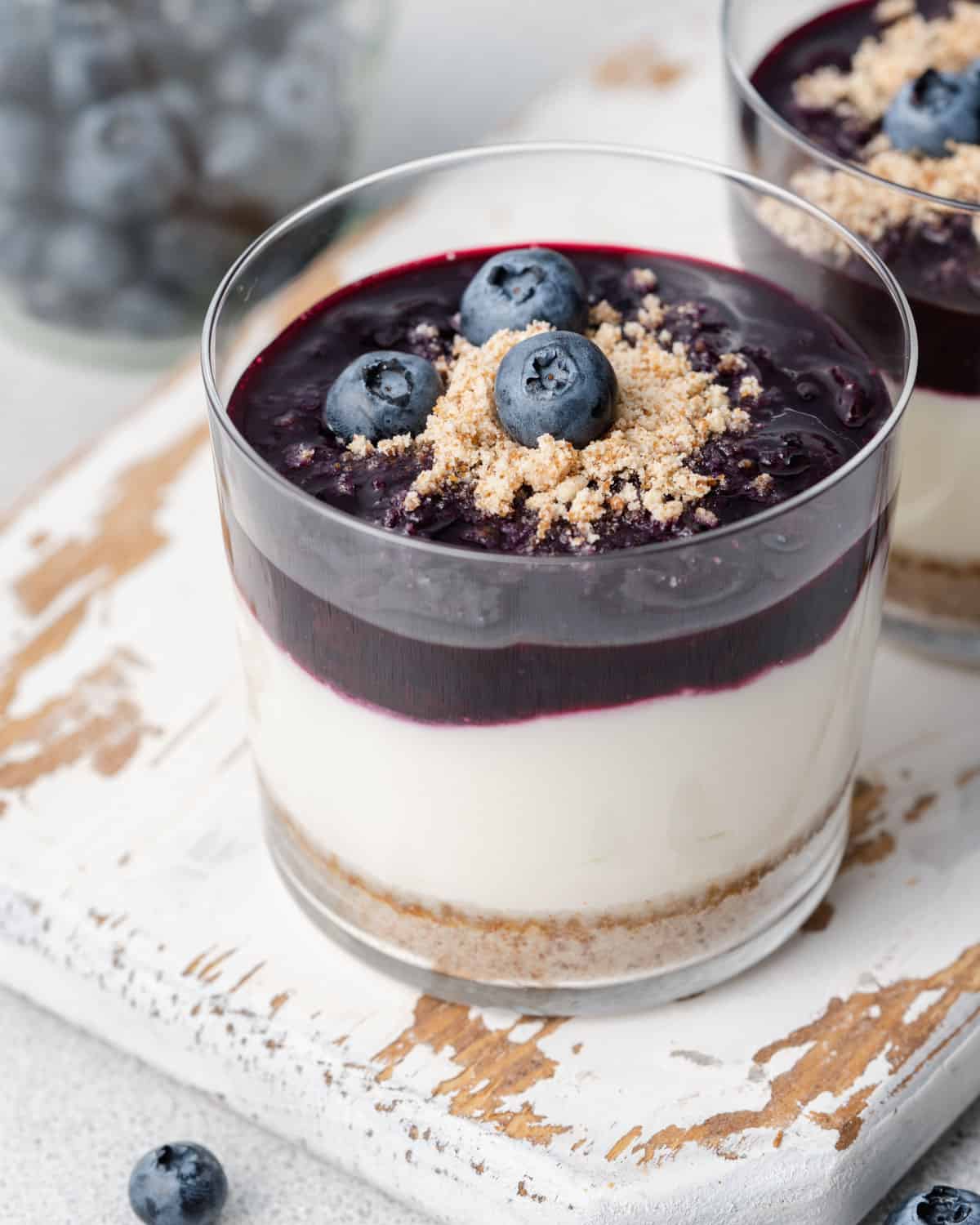 a cup with no-bake cheesecake topped with blueberry sauce.