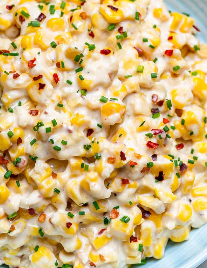 close up of creamy corn recipe topped with chili flakes on a round plate 