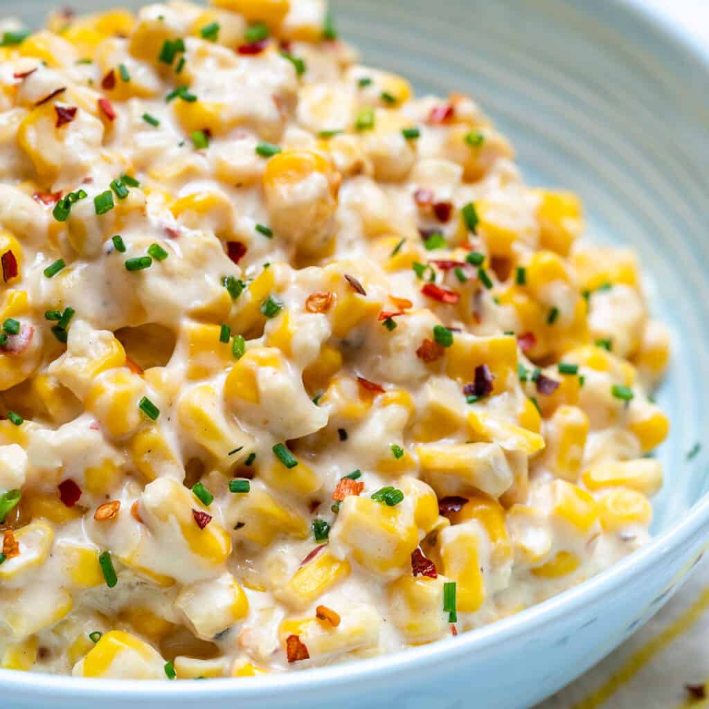 close up side shot of creamy corn in a white plate 