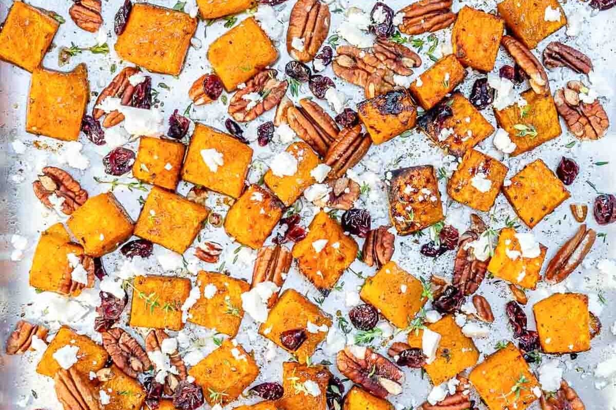 roasted butternut squash on a pan with pecans and feta cheese.