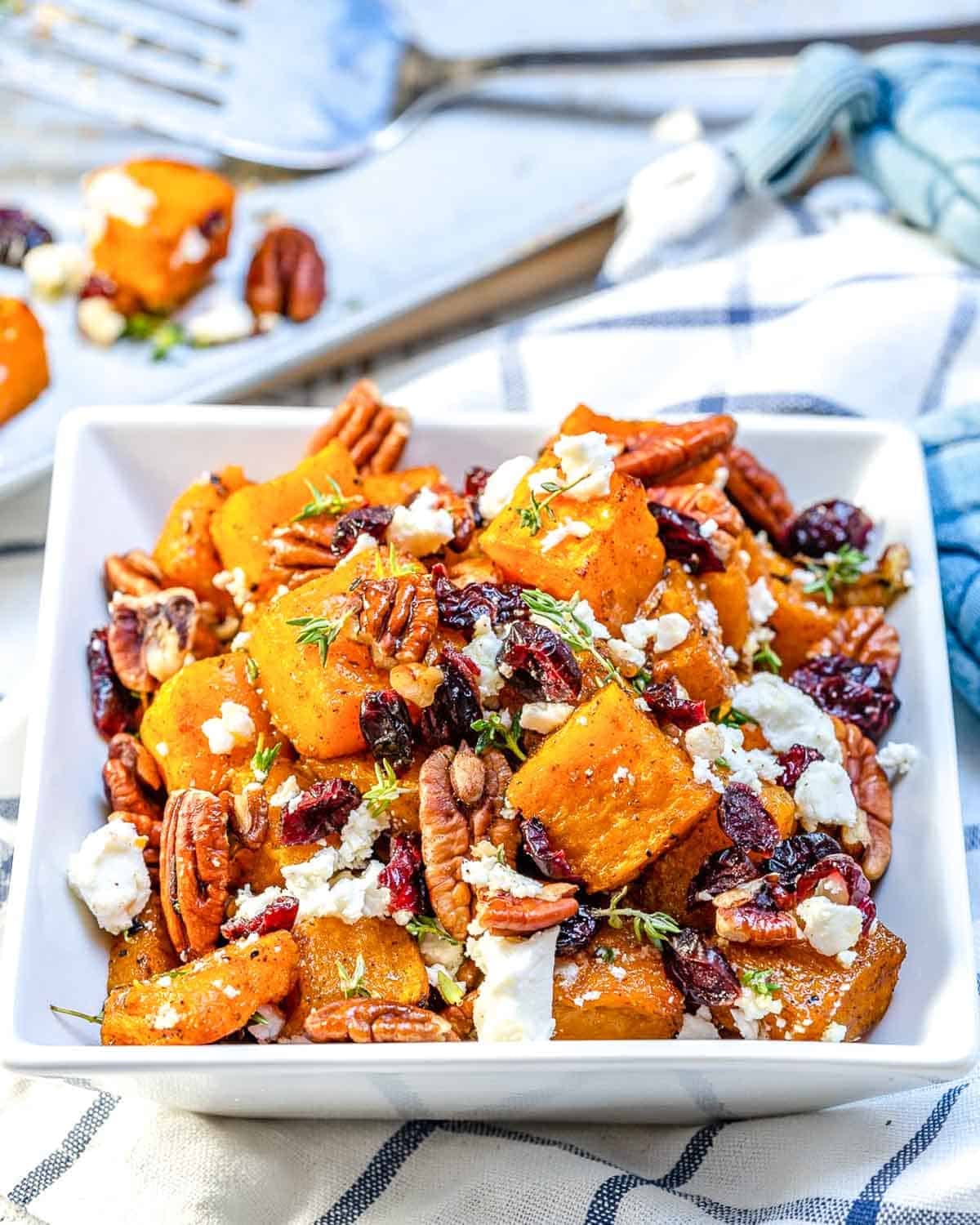 a bowl with honey roasted butternut squash made with feta cheese and pecans.