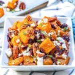 honey roasted butternut squash bites with feta cheese and pecans in a bowl.