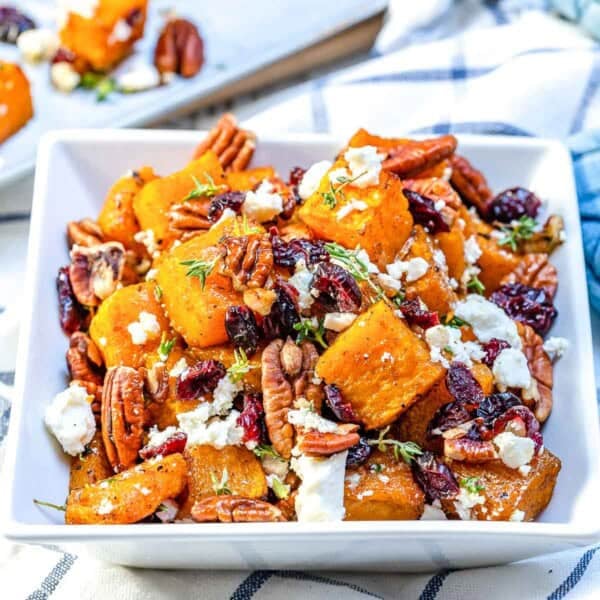 honey roasted butternut squash bites with feta cheese and pecans in a bowl.