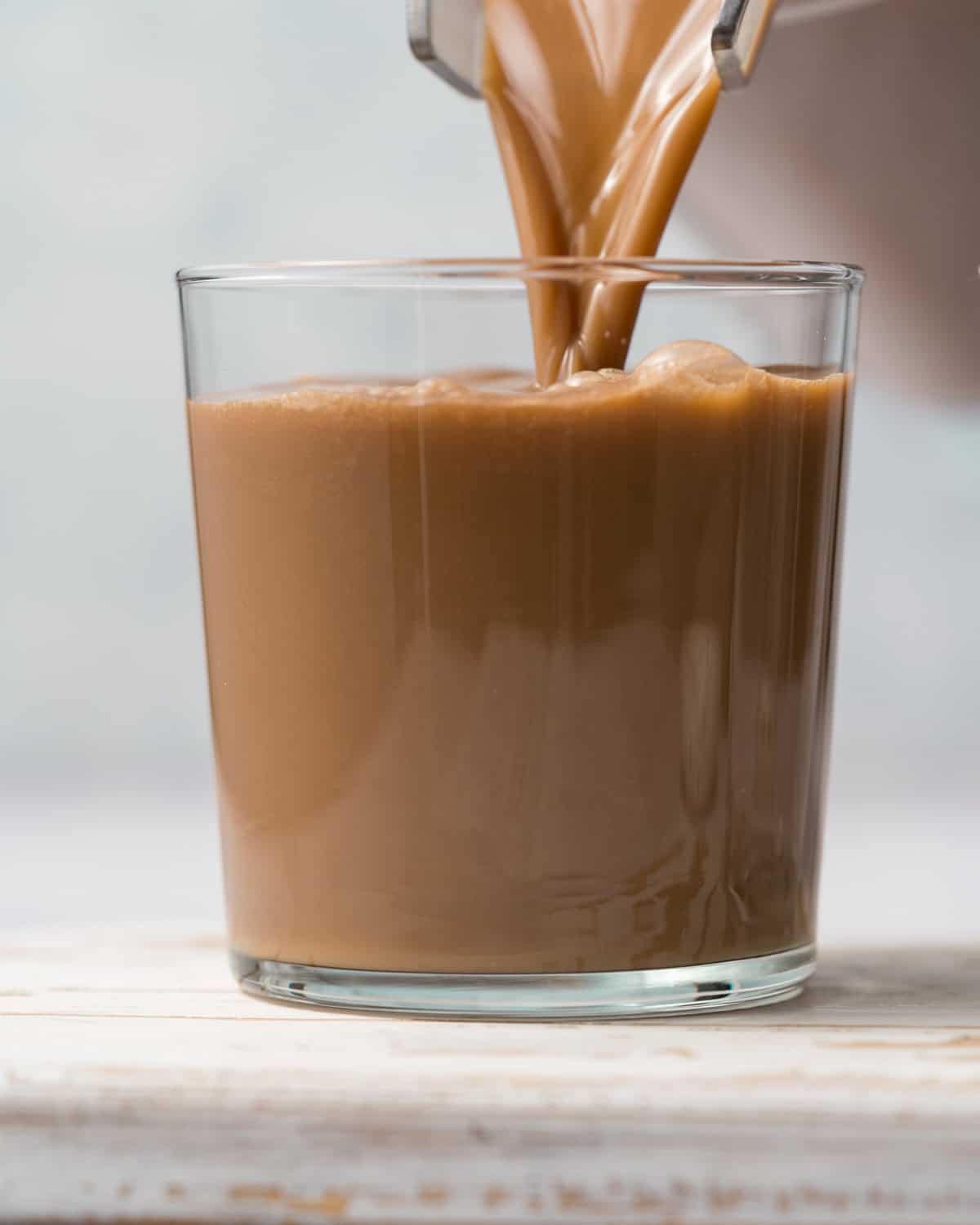 protein shake being pour in a glass cup.