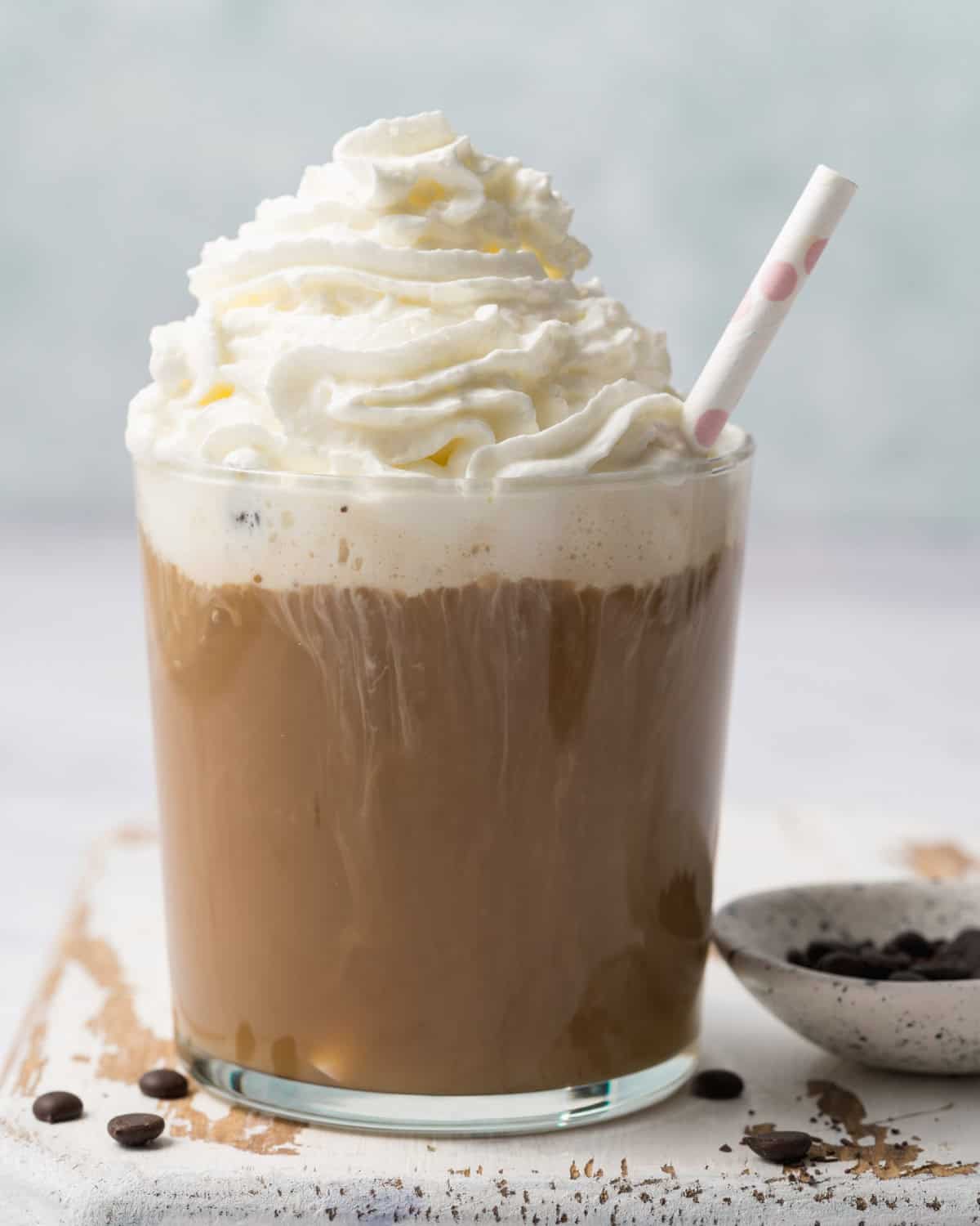 whipped cream is added over the mocha shake in a cup.