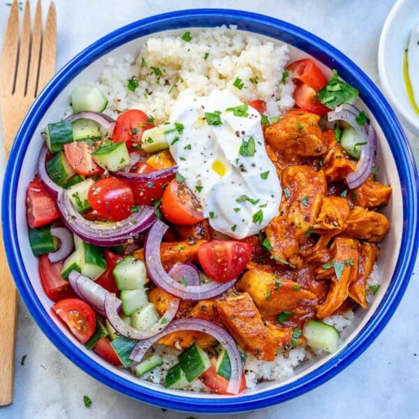 a blue bowl with Moroccan chicken served with couscous and salad.