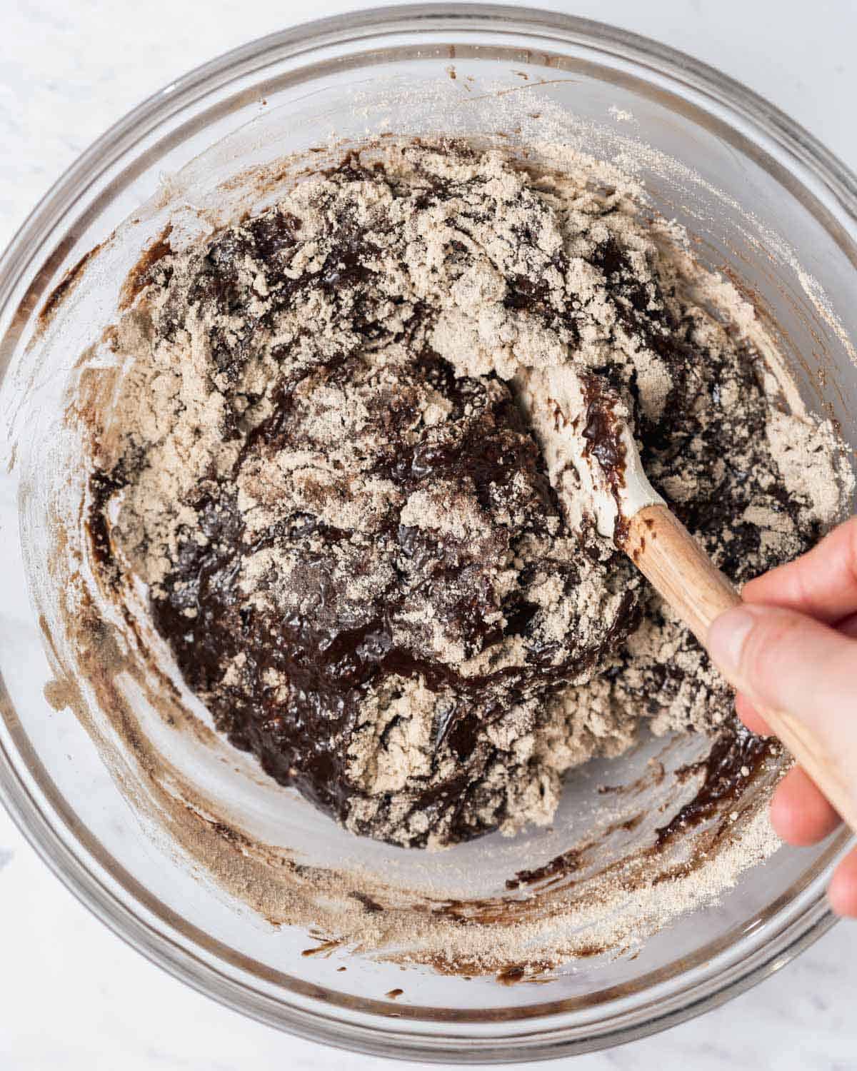 hand mixing protein powder with chocolate mix in a bowl.