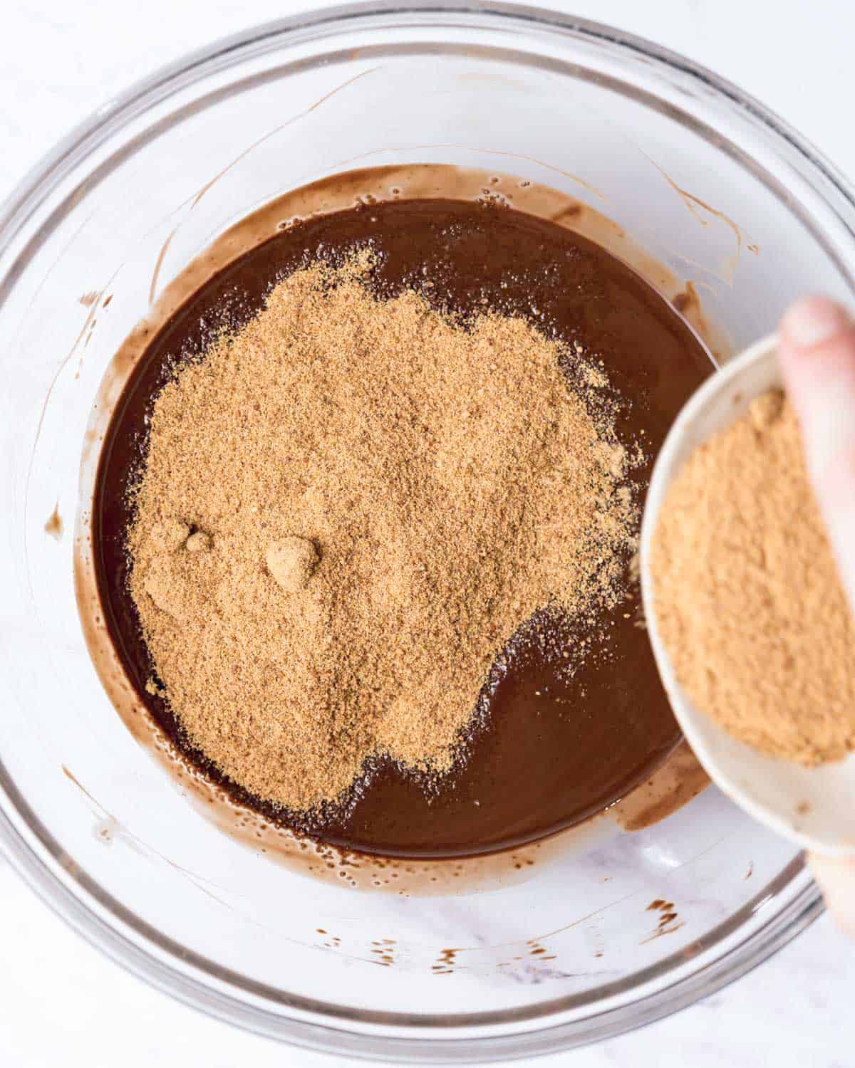 coconut sugar added over the melted chocolate in a bowl.