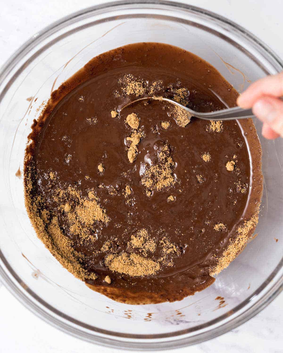 hand mixing the coconut sugar with the melted chocolate.