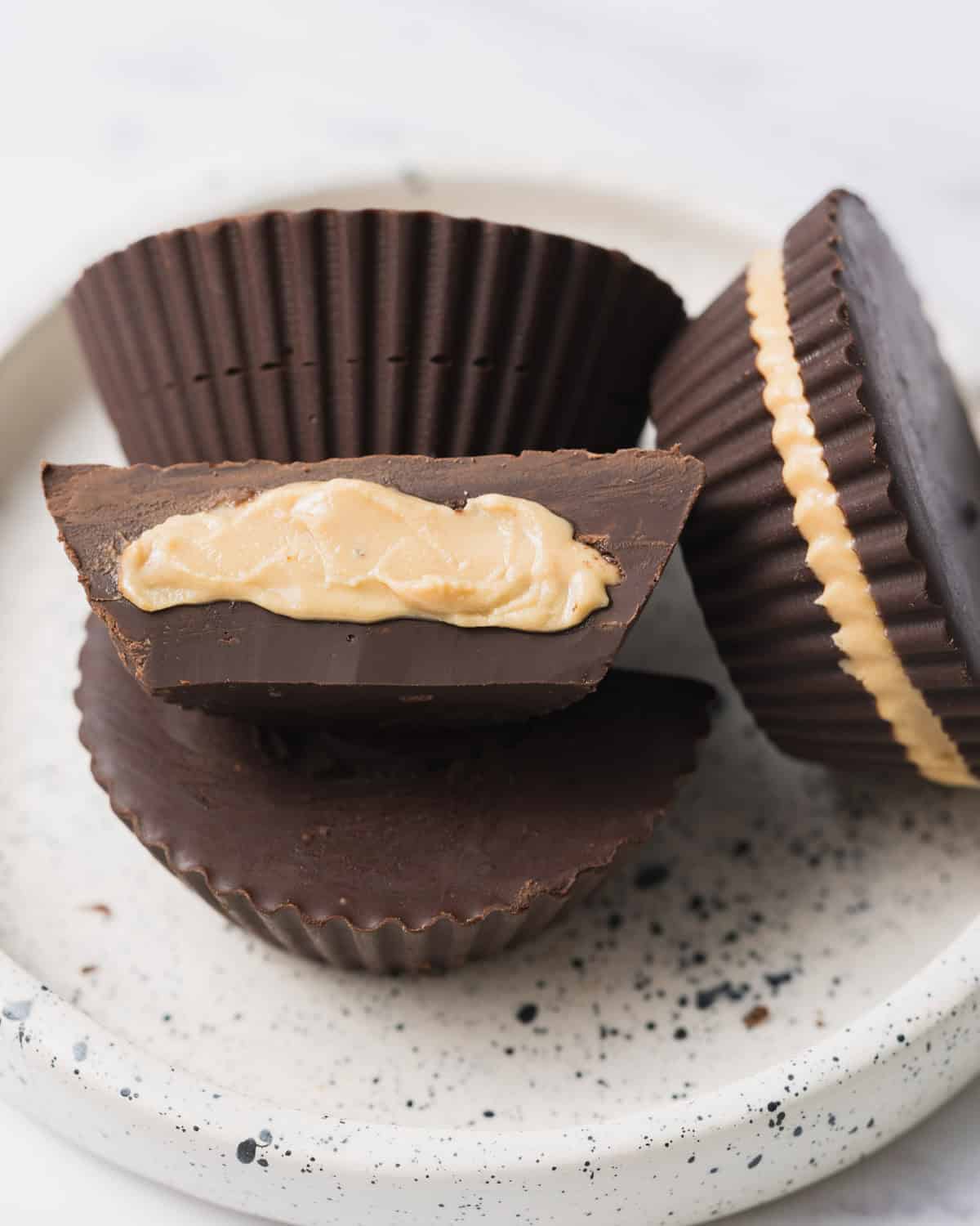 peanut butter cups on a plate with one cut in half and facing up.