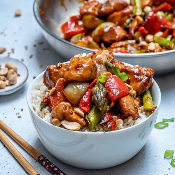 side shot of a white bowl with kung pao chicken served over rice