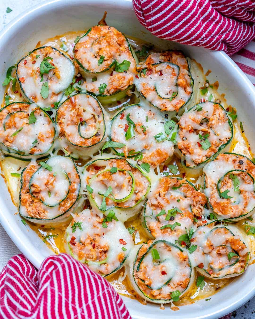 oven mitt holding a baking dish with zucchini enchilada roll ups