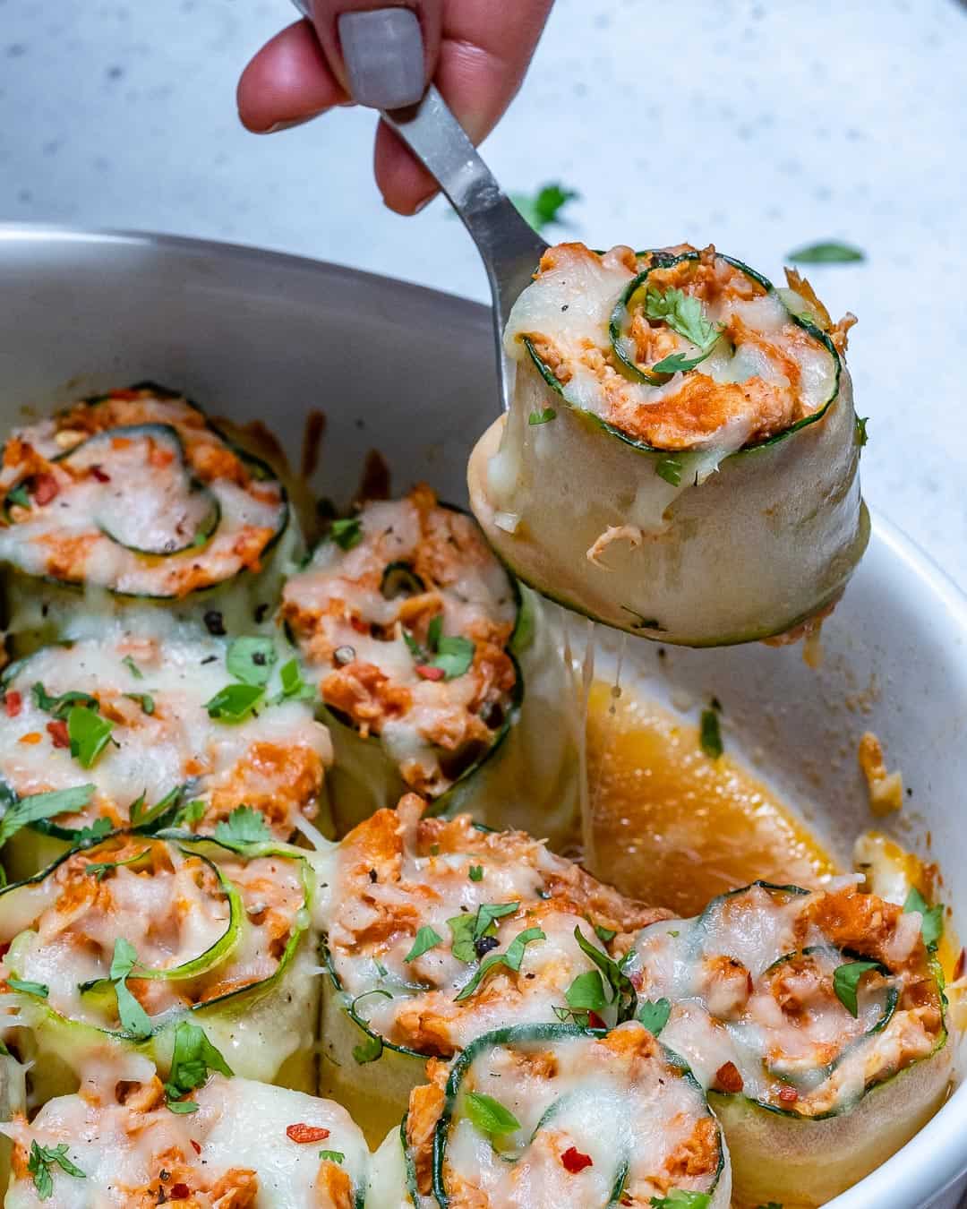 enchilada roll up being lifted from the dish with a spoon