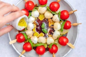 drizzling oil over the tomato mozzarella skewers.