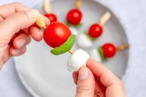 placing the mozzarella, basil, and tomatoes on a mini wooden skewer.