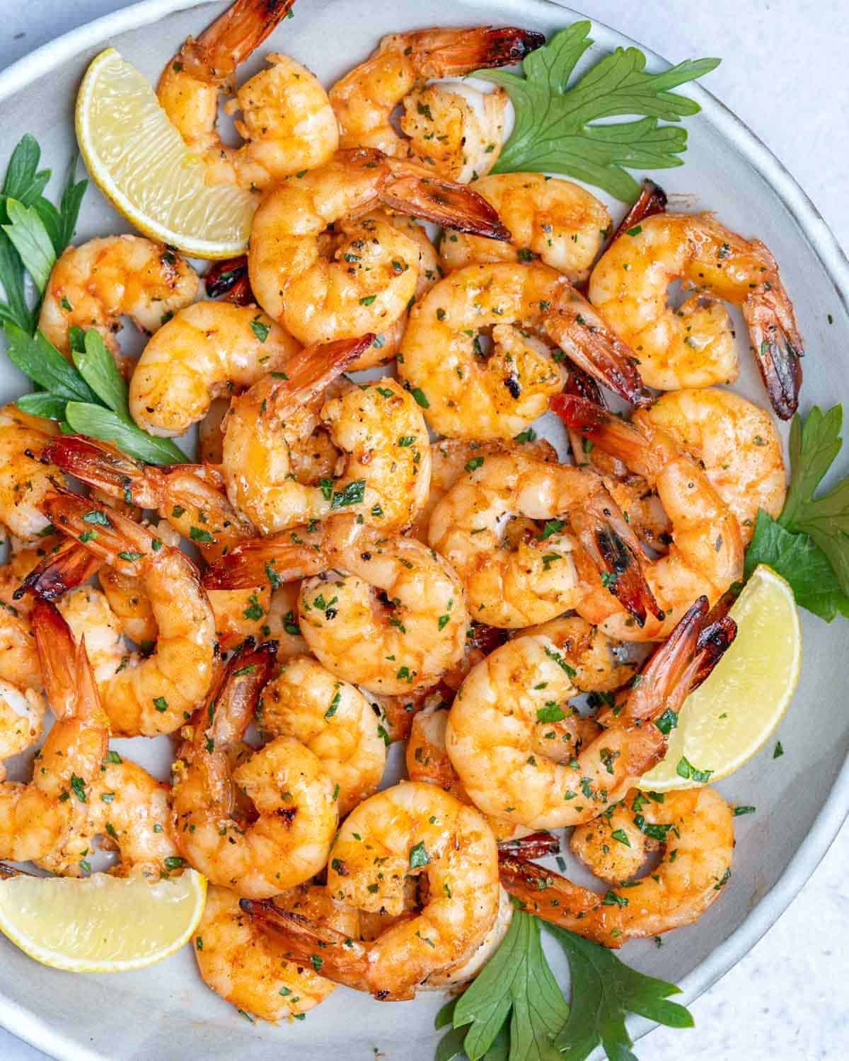 grilled shrimp on a plate served with lemon wedges.