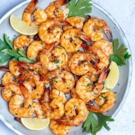 grilled shrimp on a plate with lemon garnishes.