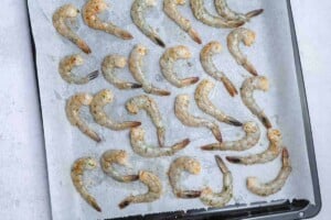 Shrimp added to a sheet pan to broil.