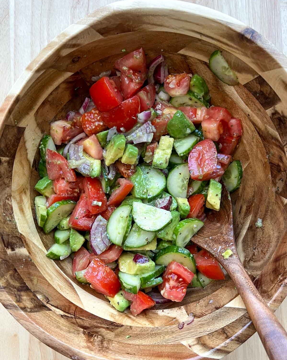 salad ingredients mixed together in a wooden bowl.