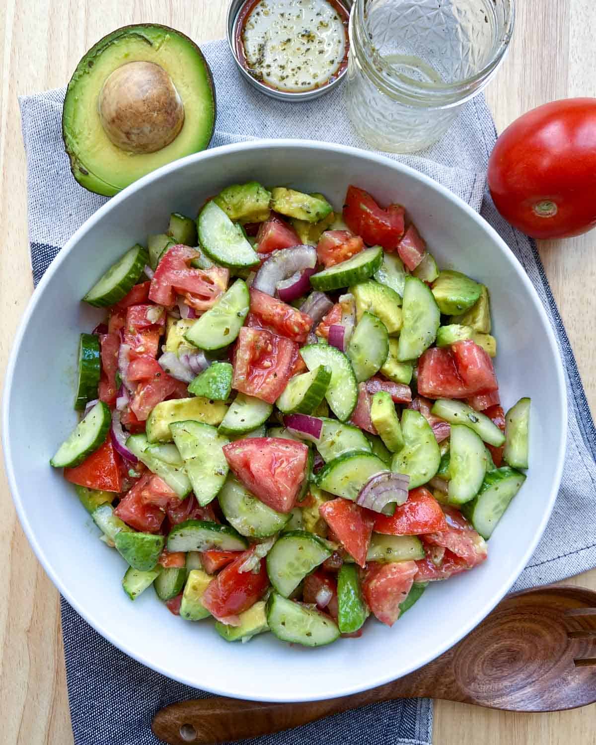 tomato and avocado salad with cucumber in a white dish.