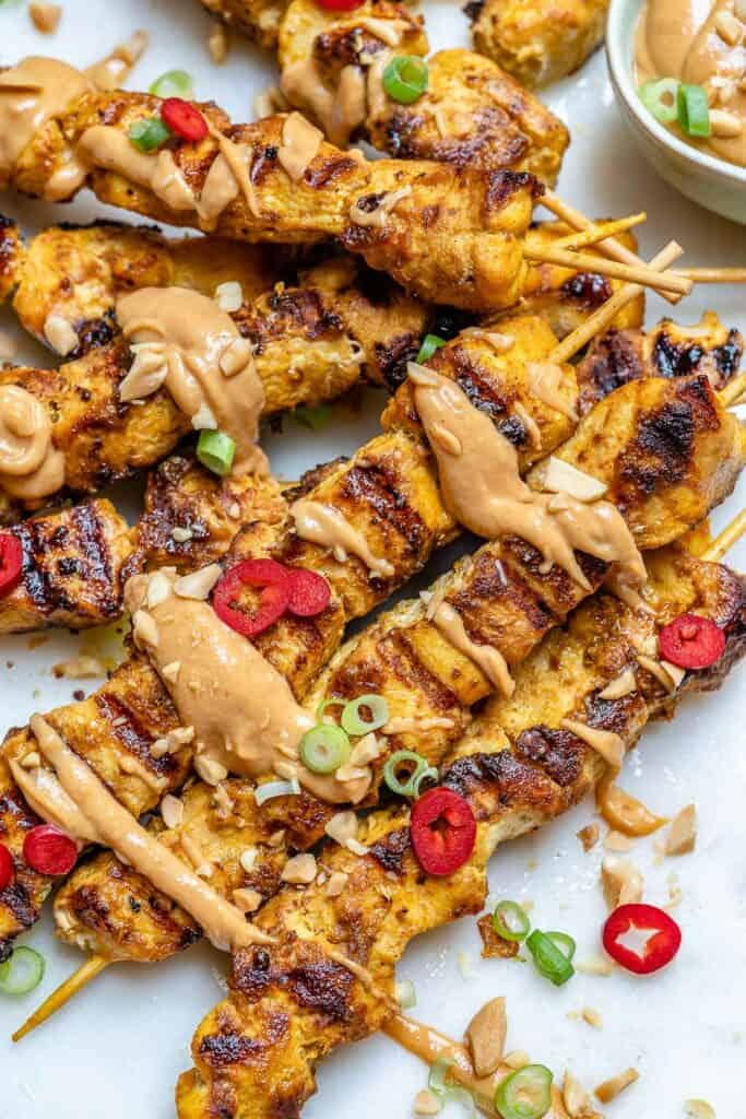 close up view of grilled chicken satay with peanut sauce drizzle 