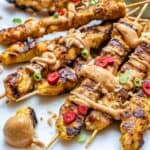 side shot of chicken satay skewers with peanut sauce
