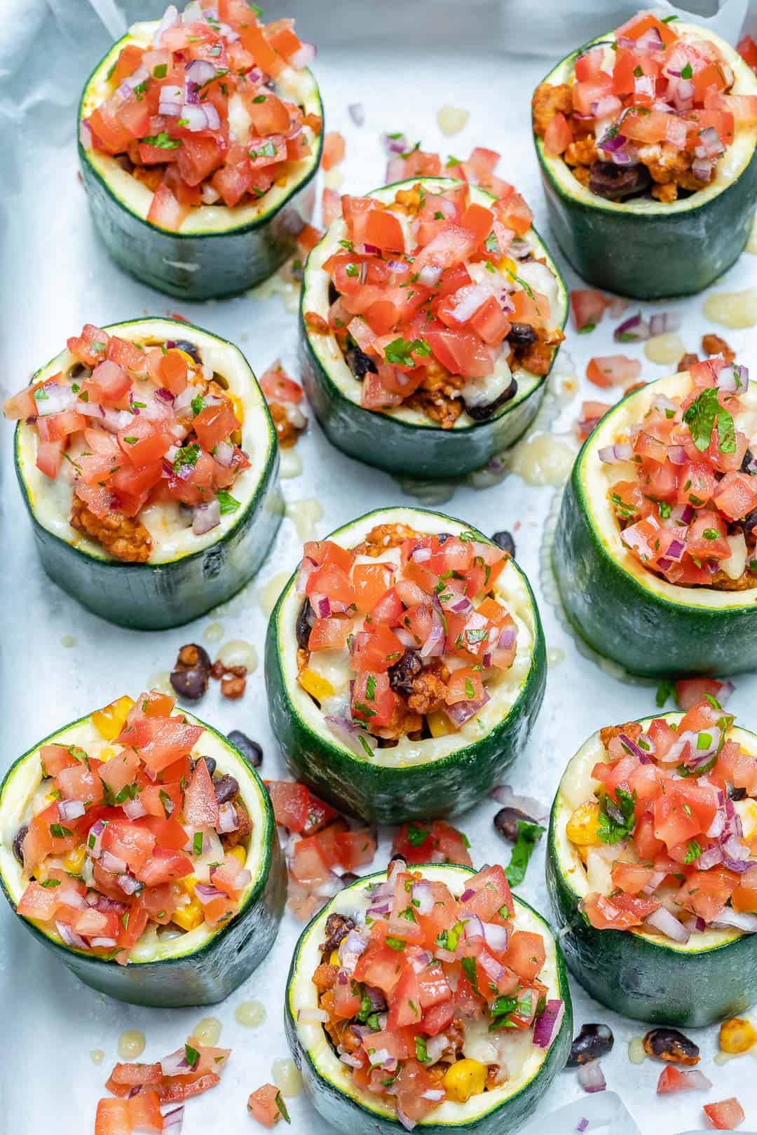 stuffed zucchini cups lined up on a sheet pan tray.