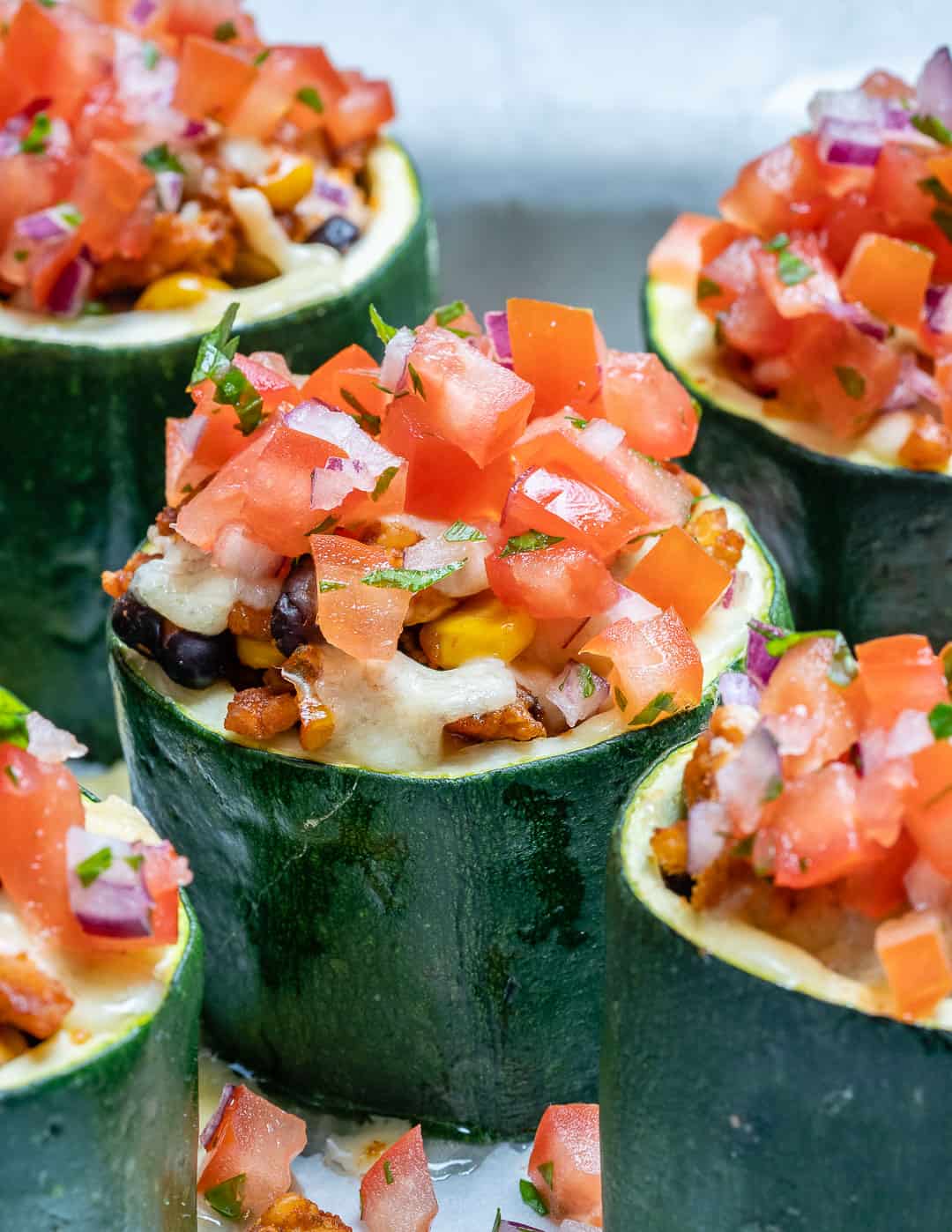 zucchini cups filled with cooked taco beef and chopped tomatoes.